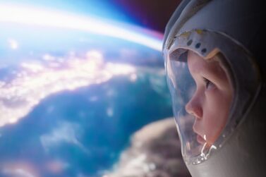 Little,Boy,With,An,Astronaut,Helmet,Looks,At,Earth,And